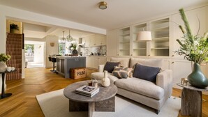 Ein geräumiges Wohnzimmer mit einer Couch, einem Couchtisch und Blick zur Küche.