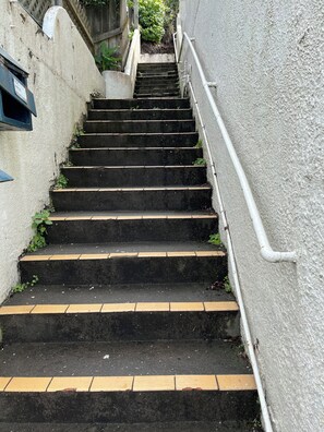 Eine Treppe führt nach draußen zu einem Gebäude mit einer strukturierten Wand und einem Metallgeländer.