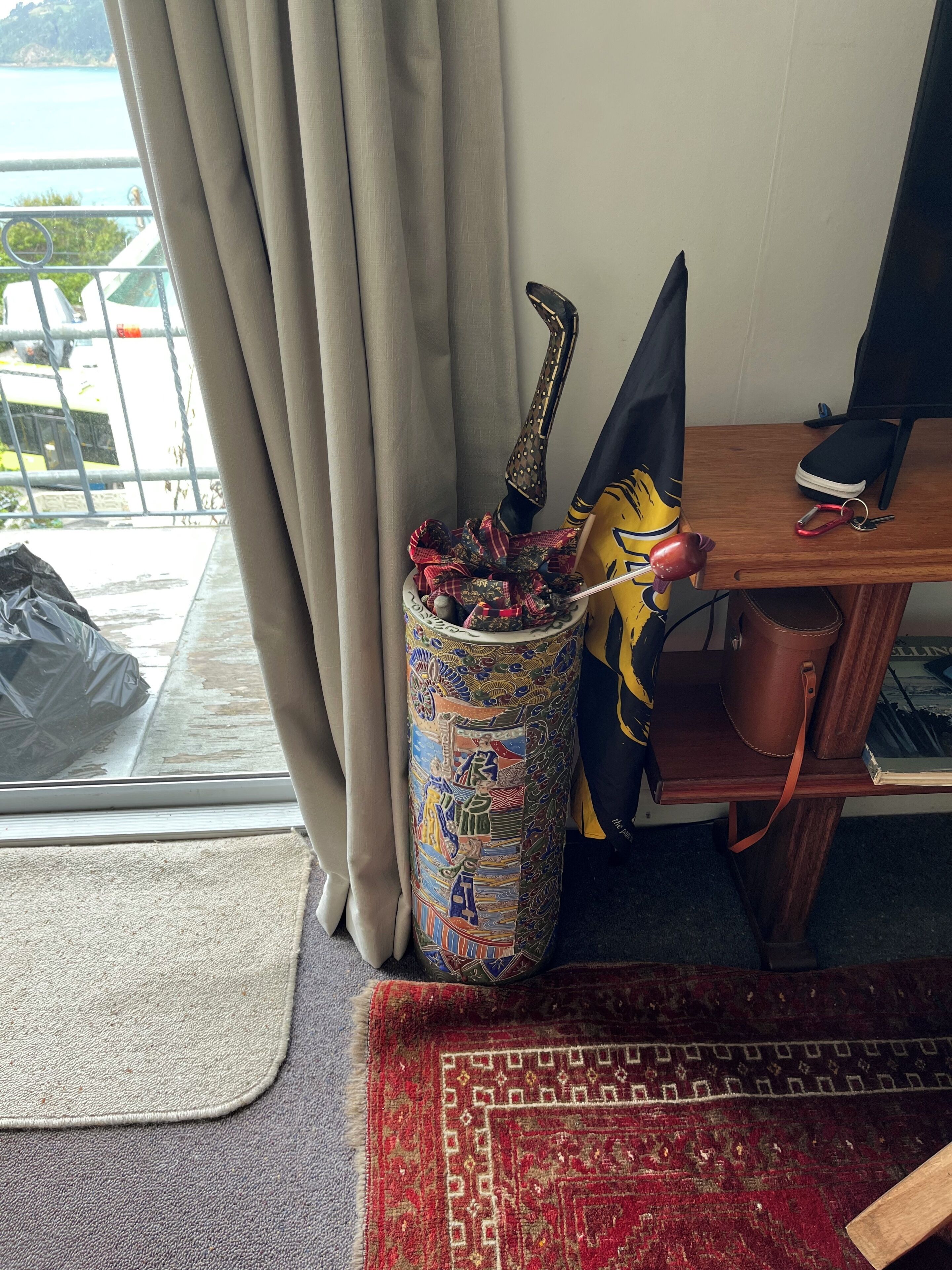 Una habitación con vistas a un cuerpo de agua, una ventana con cortinas, un escritorio con un ordenador, un florero con un adorno y una alfombra en el suelo.