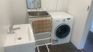 Une petite salle de bain équipée d’un lavabo, d’un miroir, d’un porte-serviettes et d’un lave-linge Bosch.