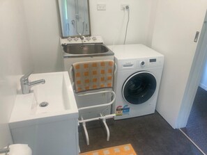 Ein kleines Badezimmer mit Waschbecken, Spiegel, Handtuchhalter und einer Bosch Waschmaschine.