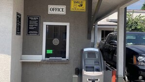 Vance Motel-reception med et overvågningskamera, en pengeautomat og en parkeret bil i nærheden.