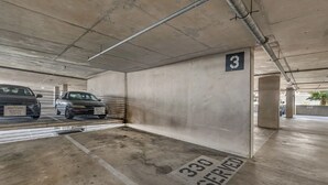 Un parcheggio con pareti in cemento, un cartello con il numero 3 e la segnaletica 'riservato a numero 330'.