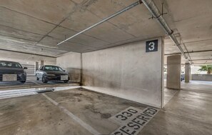 Eine Parkgarage mit Betonwänden, einem Schild mit der Nummer 3 und einem Hinweisschild für reservierte Plätze, Nummer 330.