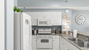 Una cucina moderna con mobili bianchi, un forno a microonde integrato, un fornello e un lavello.