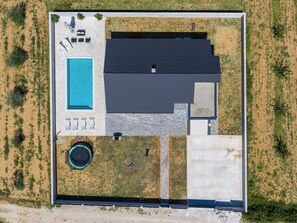 An aerial view of a property with a swimming pool, lounge chairs, a covered patio, and a large building with a dark roof. - Vila Nik by Interhome (Zadar/Sukošan)