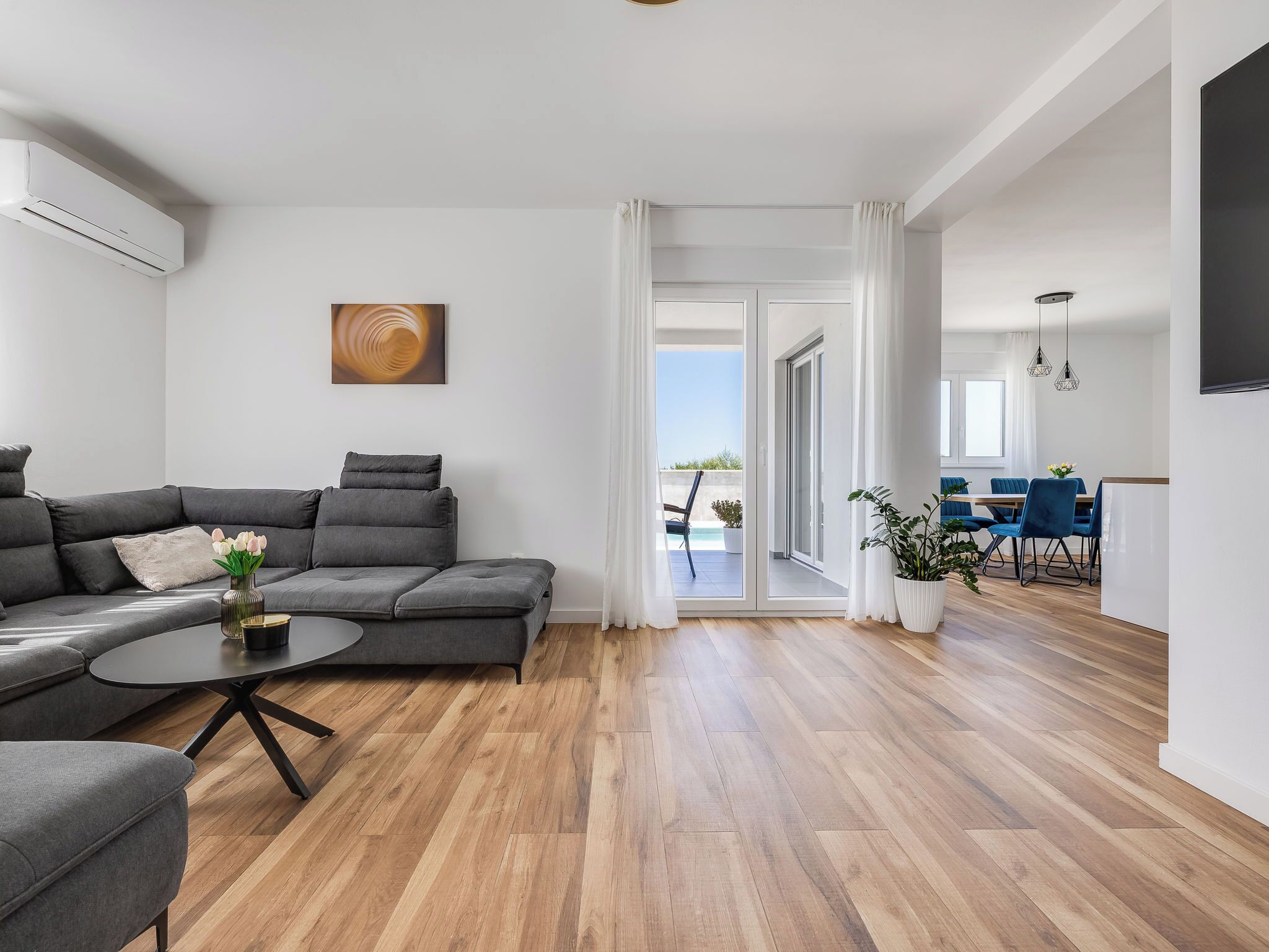 A modern living room with a grey sectional sofa, a round coffee table, and a painting on the wall.