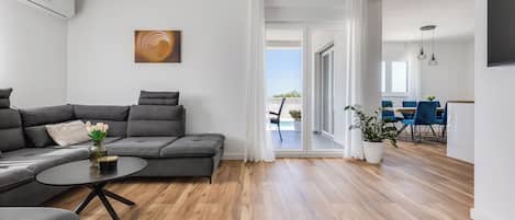 A modern living room with a grey sectional sofa, a round coffee table, and a painting on the wall.
