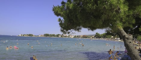 A beach scene with people swimming and sunbathing.