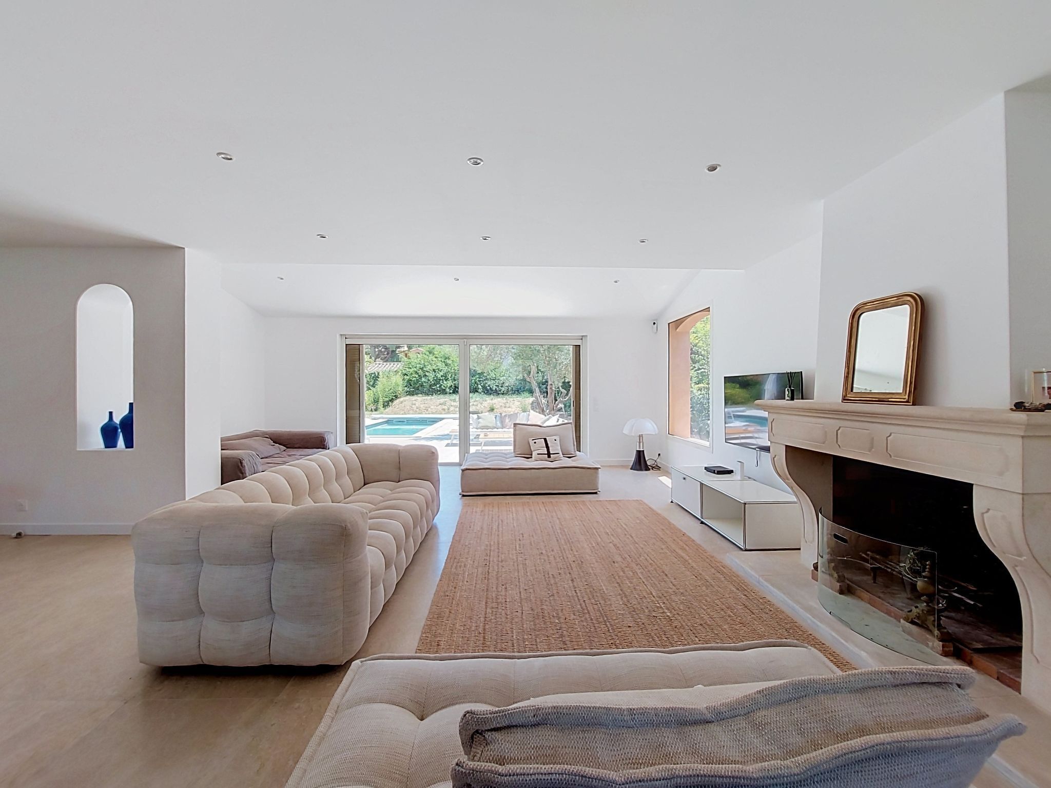 A modern living room with a large sectional sofa, a fireplace, and a view of a pool.