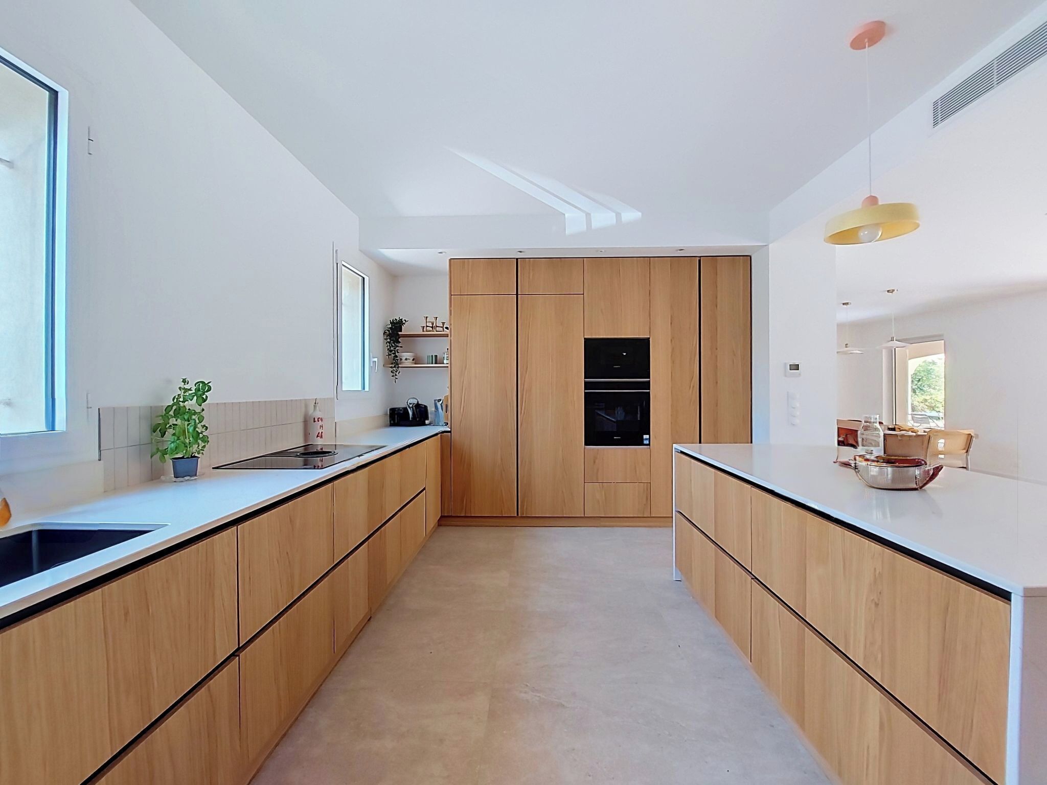 A modern kitchen with wooden cabinets, a central island, and pendant lighting.