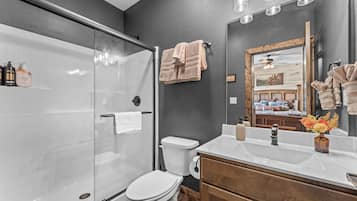 Ein modernes Badezimmer mit Glasdusche, weißer Toilette und Waschtisch mit Spiegel.