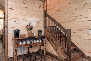 A wooden interior with a staircase, a bar area with stools, and a coffee machine. - NEW! Tall Timbers! Private Indoor Pool! (Hollister)