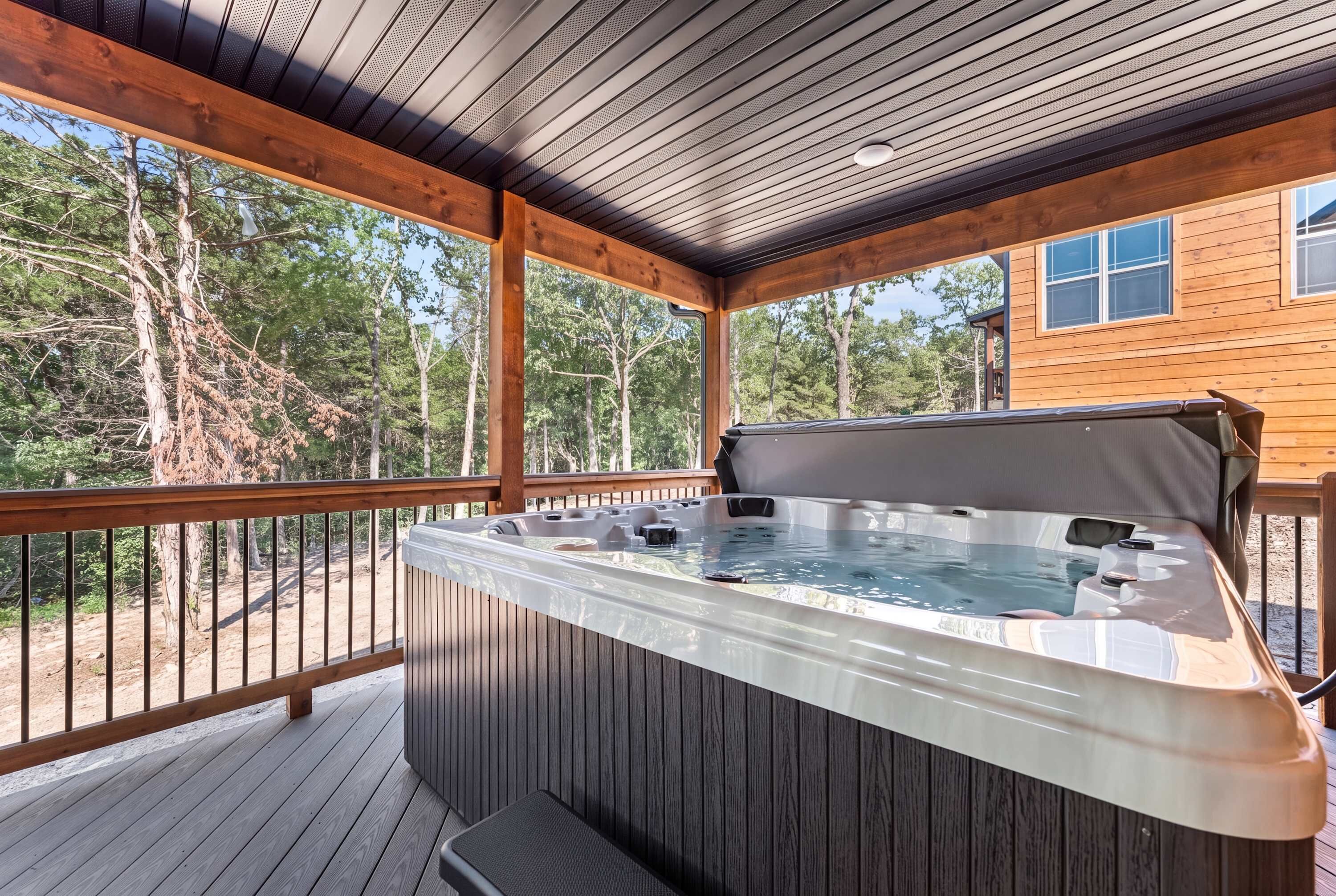 Un bain à remous sur une terrasse en bois, avec vue sur les arbres.