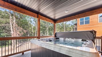 Un bain à remous sur une terrasse en bois, avec vue sur les arbres.