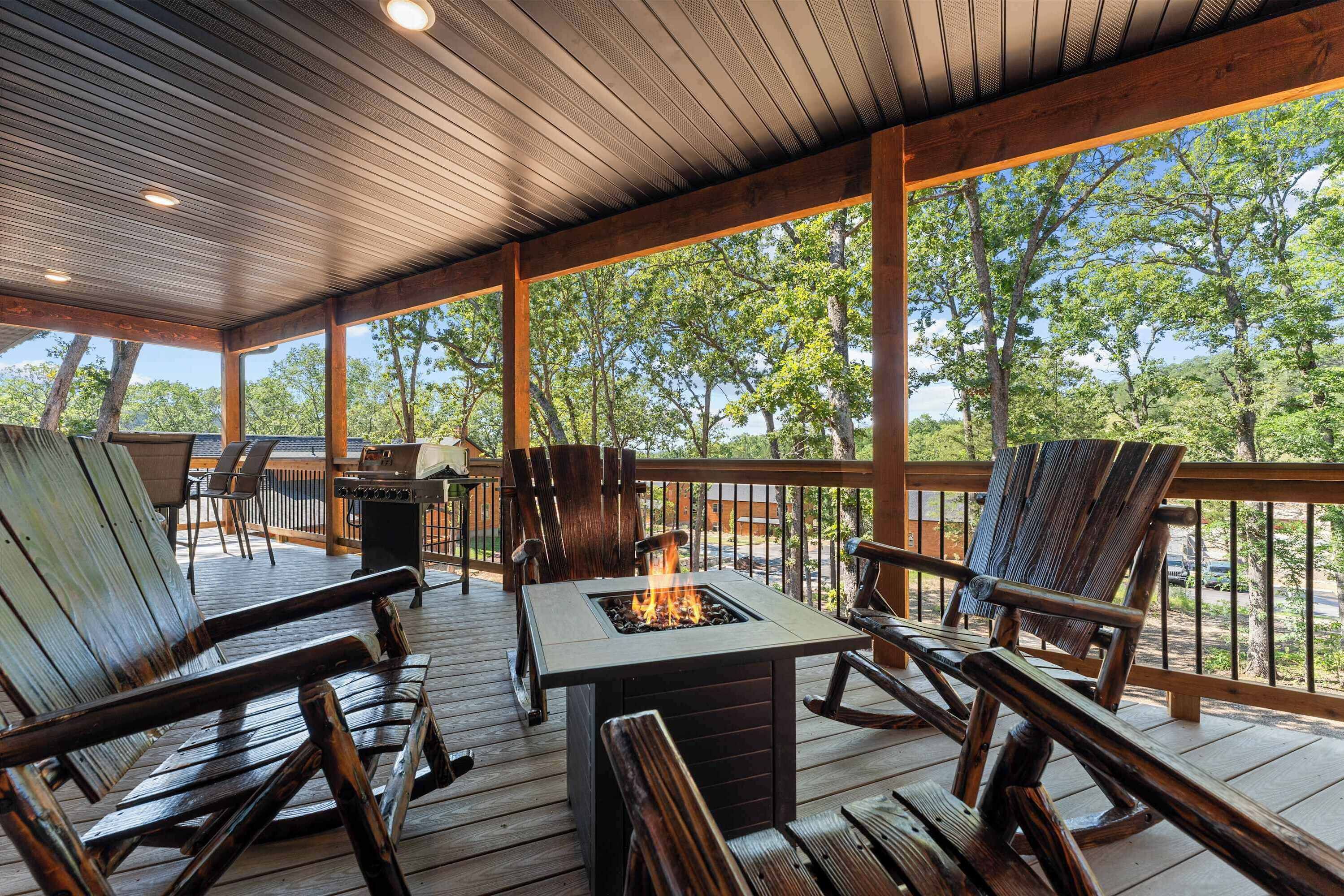 Una terraza exterior con mobiliario de madera, un brasero y vistas a árboles.
