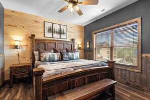 A wooden-framed bed with a headboard, two bedside tables, a bench, and a ceiling fan. - New Cabin in Tall Timbers! Private Indoor Pool! (Hollister)
