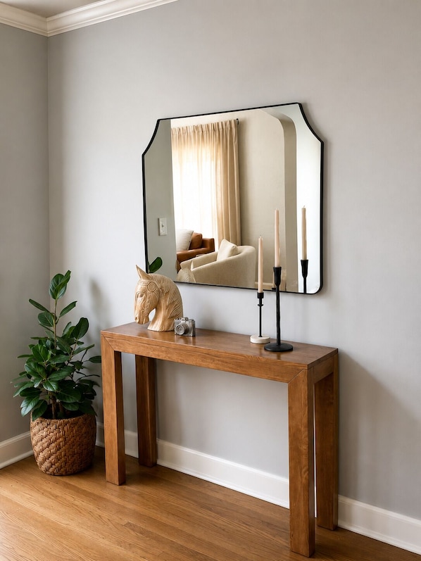 A wooden console table with a mirror, a potted plant, and a candle holder.