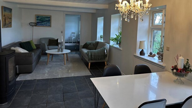 A modern living room with a dining area, a chandelier, and a view of the outdoors. - Enjoy island life in a Sejerø holiday home (Sejerø)