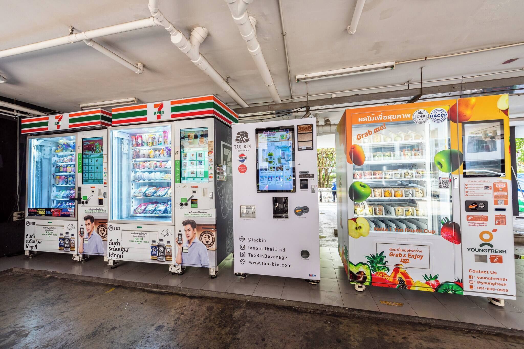 Diverses màquines expenedores amb opcions de begudes i una botiga 7-Eleven al fons.