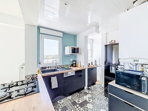 Eine kompakte Küche mit eingebautem Herd, einer Kaffeemaschine und einem Kühlschrank.