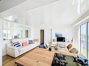 Ein modernes Wohnzimmer mit einem weißen Sofa, einem Holzesstisch und einem großen Fenster.