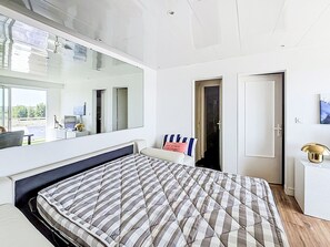 A modern bedroom with a large bed, a mirrored wall, and a view of the outdoors. - Résidence de la Mer by Interhome (Saint Malo)