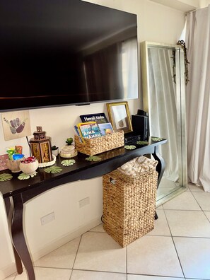 A living room with a flat-screen TV mounted on the wall, a black entertainment unit, and a woven basket on the floor. - Cozy Studio Near Waikiki Beach (Honolulu)
