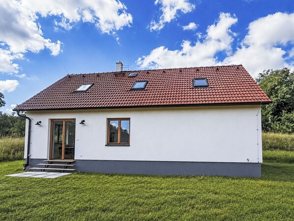 A single-story house with a red-tiled roof, a front door, and two windows.