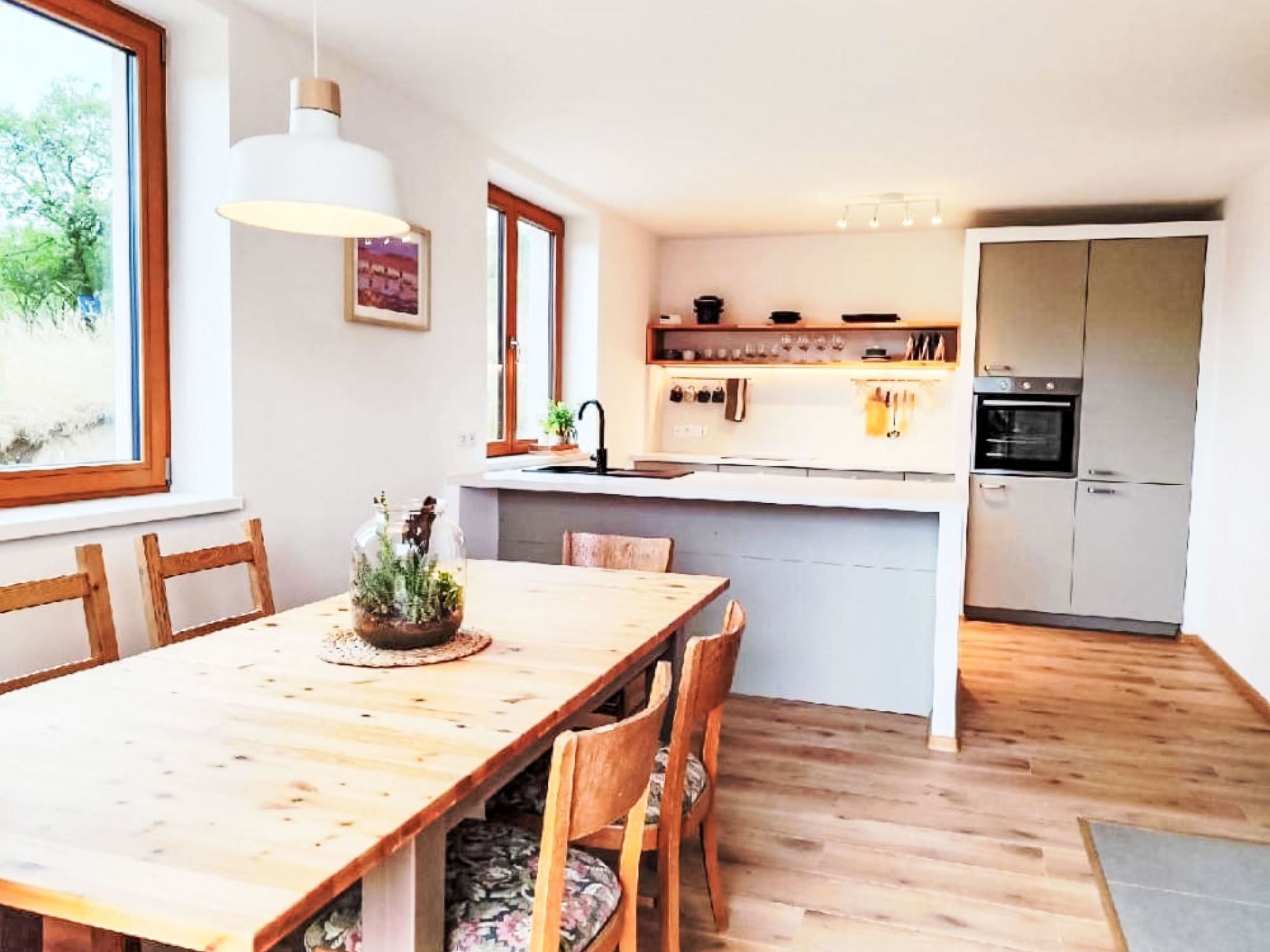 Una cocina moderna con una mesa de comedor de madera, sillas y un horno empotrado.
