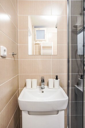 Une salle de bain avec un lavabo, un miroir et une douche.