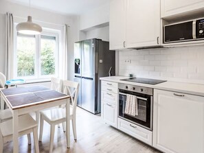 A modern kitchen with white cabinetry, a built-in oven, a microwave, and a refrigerator. - Prague Castle Oasis by Interhome (Praha/6)
