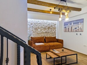 A living room with a stone wall, a brown sofa, a wooden coffee table, and a hanging light fixture. - Blazov dvor by Interhome (Zaton)