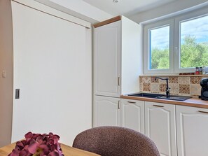 A kitchen with white cabinets, a window, and a sink. - Blazov dvor by Interhome (Zaton)