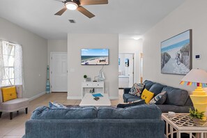 A modern living room with a sofa, a coffee table, and a TV mounted on the wall.