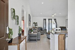 Ein modernes Wohnzimmer mit einer Couch, einem Couchtisch und einem Essbereich mit Küchenzeile.