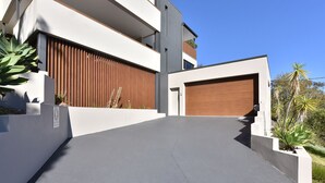 Une maison moderne à deux étages, dotée d’un garage, d’une allée et d’une clôture en bois.