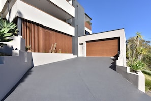 Une maison moderne à deux étages, dotée d’un garage, d’une allée et d’une clôture en bois.