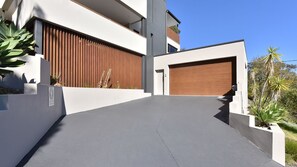Ein modernes, zweistöckiges Haus mit Garage, geneigtem Auffahrt und einem gepflegten Garten mit großen Pflanzen.