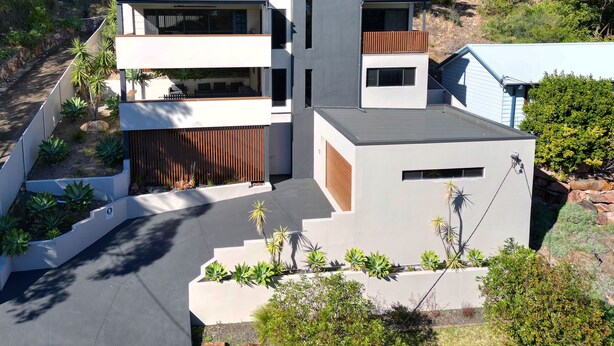 Un immeuble résidentiel moderne à plusieurs étages, doté d’un toit plat, de nombreux balcons et d’un jardin aménagé.