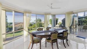 Ein Essbereich mit Tisch und Stühlen, großen Fenstern und einem Deckenventilator.