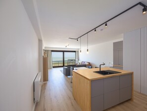 A modern kitchen with a large island, a dining area with a view, and a living space with a sofa and a table. - 8th-floor apartment with sea view (Middelkerke)