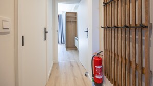 A hallway with a wooden wardrobe, a fire extinguisher, and a door leading to a room. - 8th-floor apartment with sea view (Middelkerke)