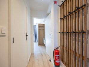 Ein Korridor mit einem Holzschrank, einem Feuerlöscher und einer Tür zu einem Zimmer.