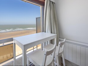 A balcony with a white table and chairs, overlooking a beach. - 8th-floor apartment with sea view (Middelkerke)