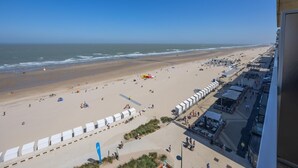 A beach view from a high vantage point, including a promenade with shops and a clear sky. - 8th-floor apartment with sea view (Middelkerke)