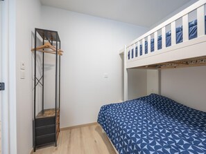 Un lit superposé avec un lit supérieur blanc et un lit inférieur recouvert d’une courtepointe à motifs bleus.