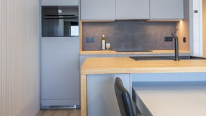 A modern kitchen with grey cabinets, a wooden countertop, a built-in oven, and a stainless steel faucet. - 8th-floor apartment with sea view (Middelkerke)