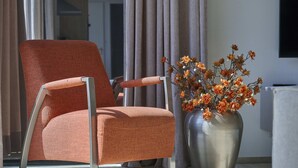Ein moderner Sessel mit Metallgestell und Stoffbezug, neben einer Vase mit orangenen Blumen.