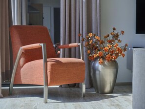 A modern armchair with a metallic frame and fabric seat, positioned next to a vase with orange flowers. - Beach lodge on the beach (Callantsoog)